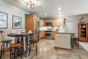 A modern kitchen with stainless steel appliances, wooden cabinets, and a central island. - Ski-In/Ski-Out Snowbird Sanctuary 687 (Mammoth Lakes)
