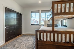 A room with a bunk bed, a dark wooden door, and a window with a view of houses. - Beautiful CreekHouse with Amazing Views 322 (Mammoth Lakes)