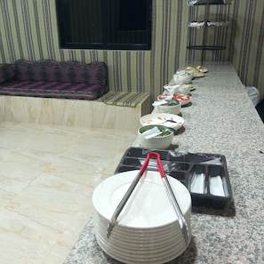 Ein reichhaltiges Buffet mit verschiedenen Schalen und Tellern auf einer Granitabdeckung.