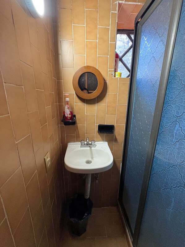 Ein Badezimmer mit Waschbecken, Spiegel, Seifenspender und Mülleimer.