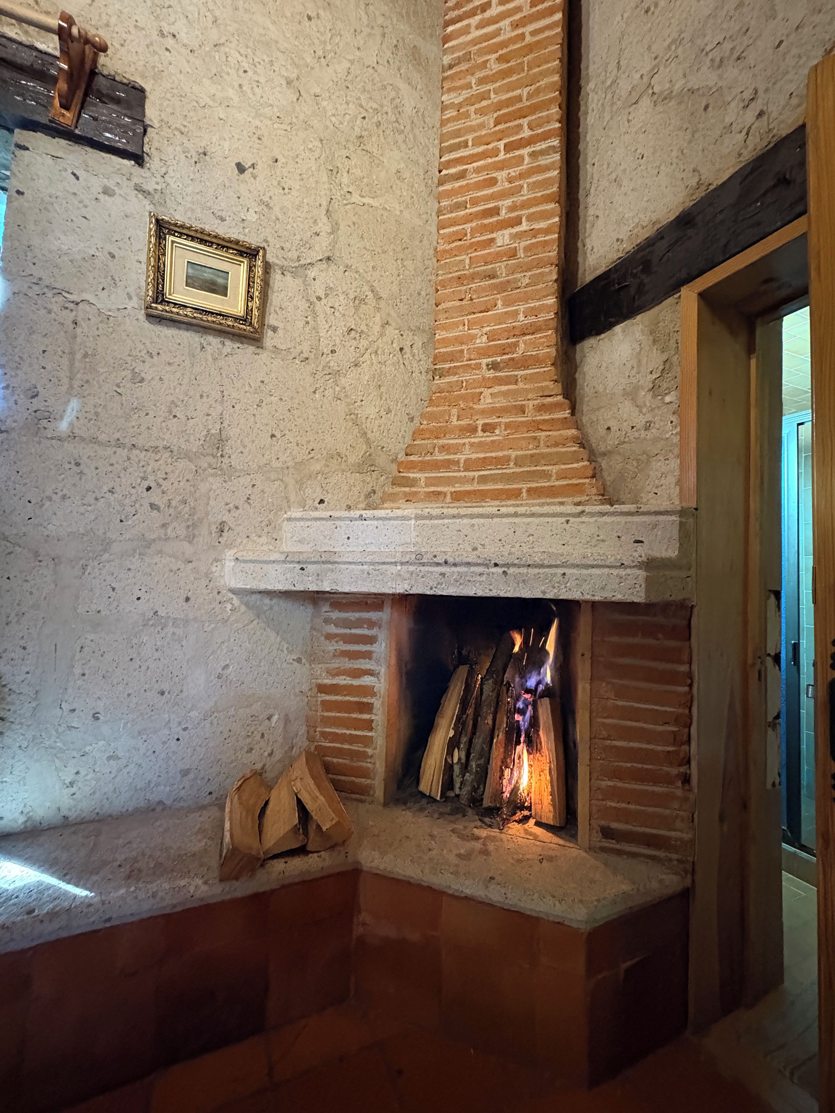 Une cheminée en briques, un tableau encadré accroché au mur et un cadre de porte en bois.