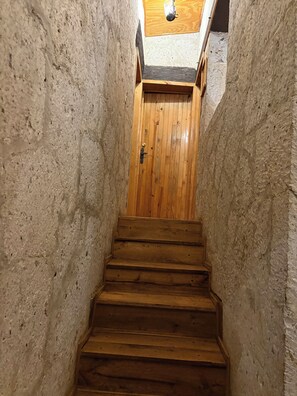 En trætrap fører op til et rum med en trädörr og et skråt loft.