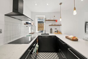 Une cuisine moderne avec des meubles noirs, un plan de travail blanc et un sol à motifs.