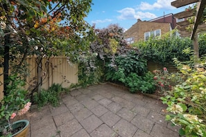 A garden with a paved patio, wooden fence, and various plants. - Bright 2 bed Chiswick by ARP Homes l 5 min tube & Heathrow (Greater London)