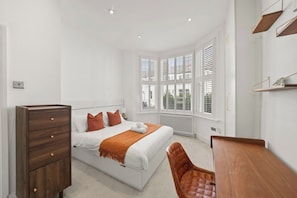 A modern bedroom with a large bed, a wooden dresser, a chair, and a bay window. - Bright 2 bed Chiswick by ARP Homes l 5 min tube & Heathrow (Greater London)