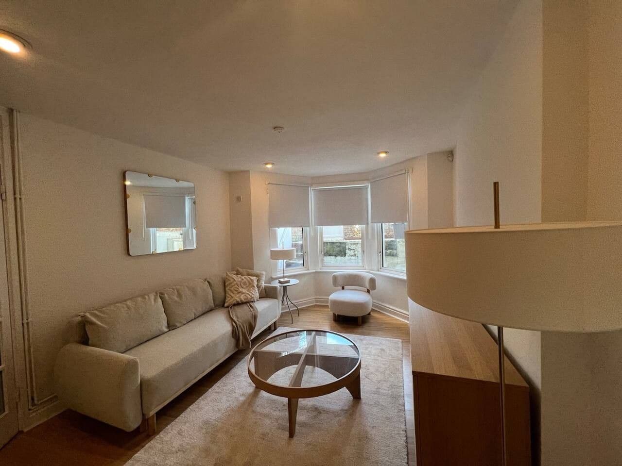 A modern living room with a sofa, a round coffee table, and a lamp.