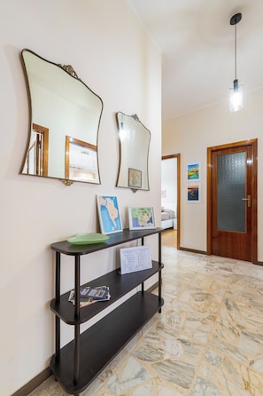 A hallway with a marble floor, a console table with a green plate, and two wall mirrors. - ElleEsse Apartment: Between Ortigia and the Archaeological Park. Two bathrooms, large living room (Siracusa)