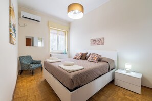 A bedroom with a bed, a chair, a bedside table, and a window. - ElleEsse Apartment: Between Ortigia and the Archaeological Park. Two bathrooms, large living room (Siracusa)