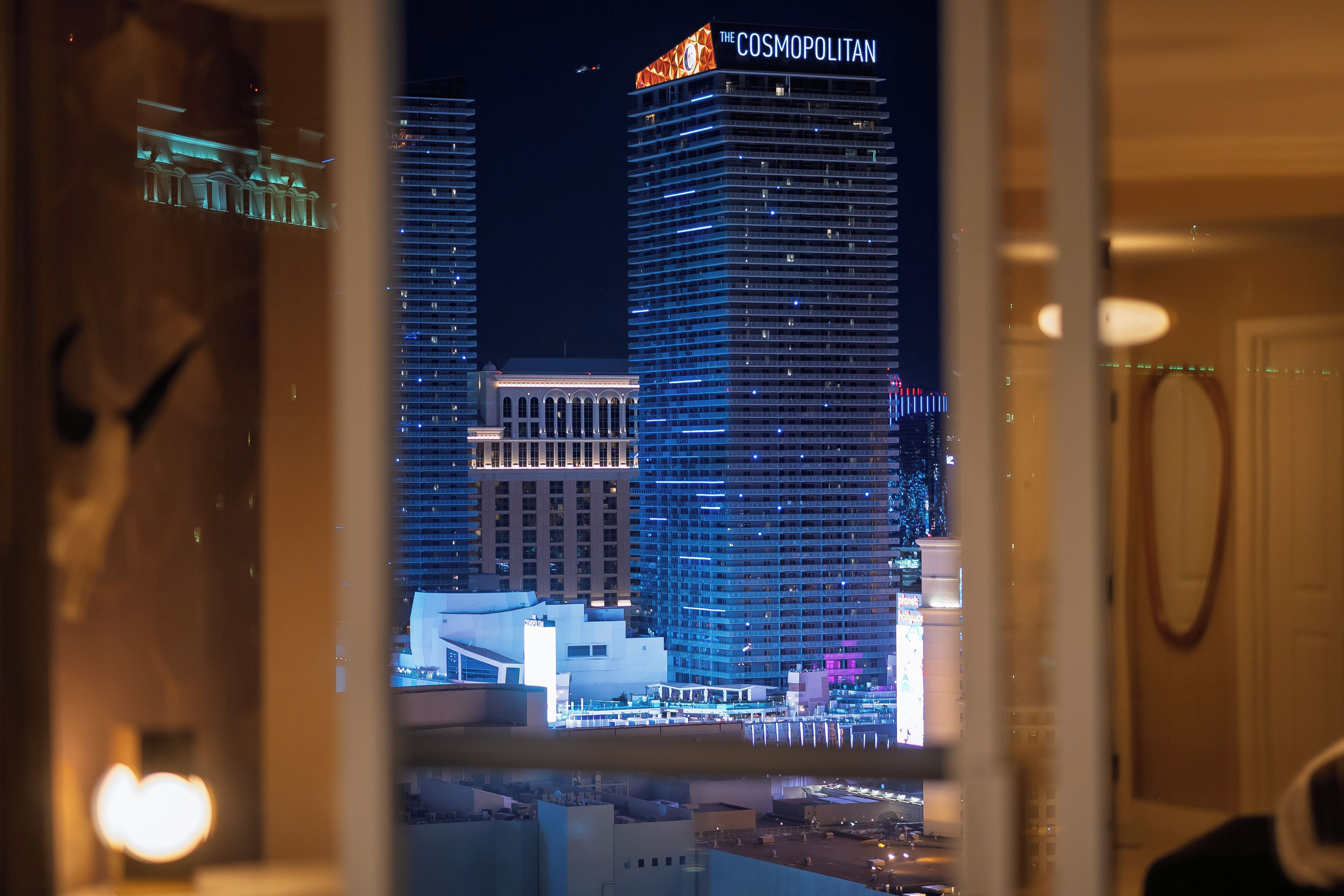 A nighttime view of a cityscape with illuminated buildings, including a prominent hotel named 'The Cosmopolitan.'