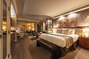 A hotel room with a large bed, bedside tables, a desk, and a seating area. - Remodeled High Floor Strip View Balcony (Las Vegas)