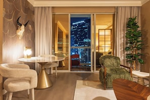 A modern hotel room with a city view, a round table, two chairs, and a large potted plant. - Remodeled High Floor Strip View Balcony (Las Vegas)