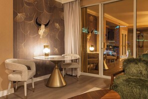Habitación de hotel moderna con una mesa redonda, dos sillas, una manta de piel y un decorado de pared con una calavera y hojas de ginkgo.