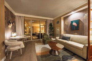 Habitación de hotel con sofá, sillas, zona de comedor y vistas al hotel.