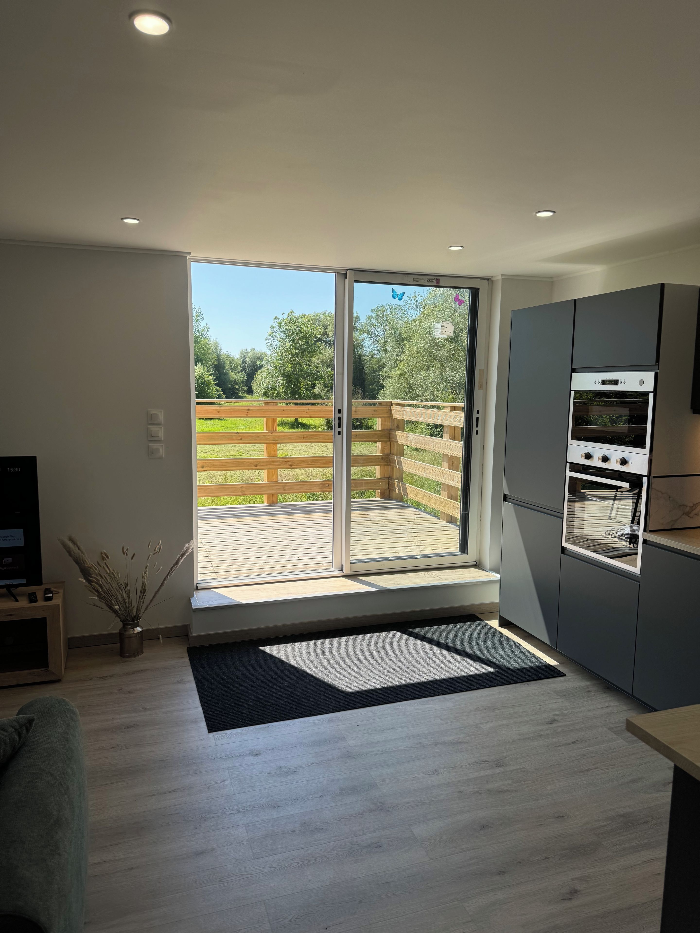 A modern kitchen with a built-in oven and a sliding glass door leading to a wooden deck.