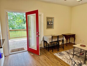 A room with a wooden floor, a dining table with chairs, a small table with a bowl, a door leading to a balcony, and a framed picture on the wall. - 2-bedroom, 1.5 bathroom house near UVA (Charlottesville)