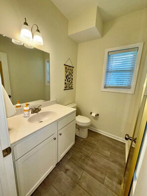 A bathroom with a sink, mirror, toilet, and a window with blinds. - 2-bedroom, 1.5 bathroom house near UVA (Charlottesville)
