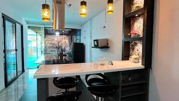 A modern kitchen with a central island, pendant lighting, and black bar stools.