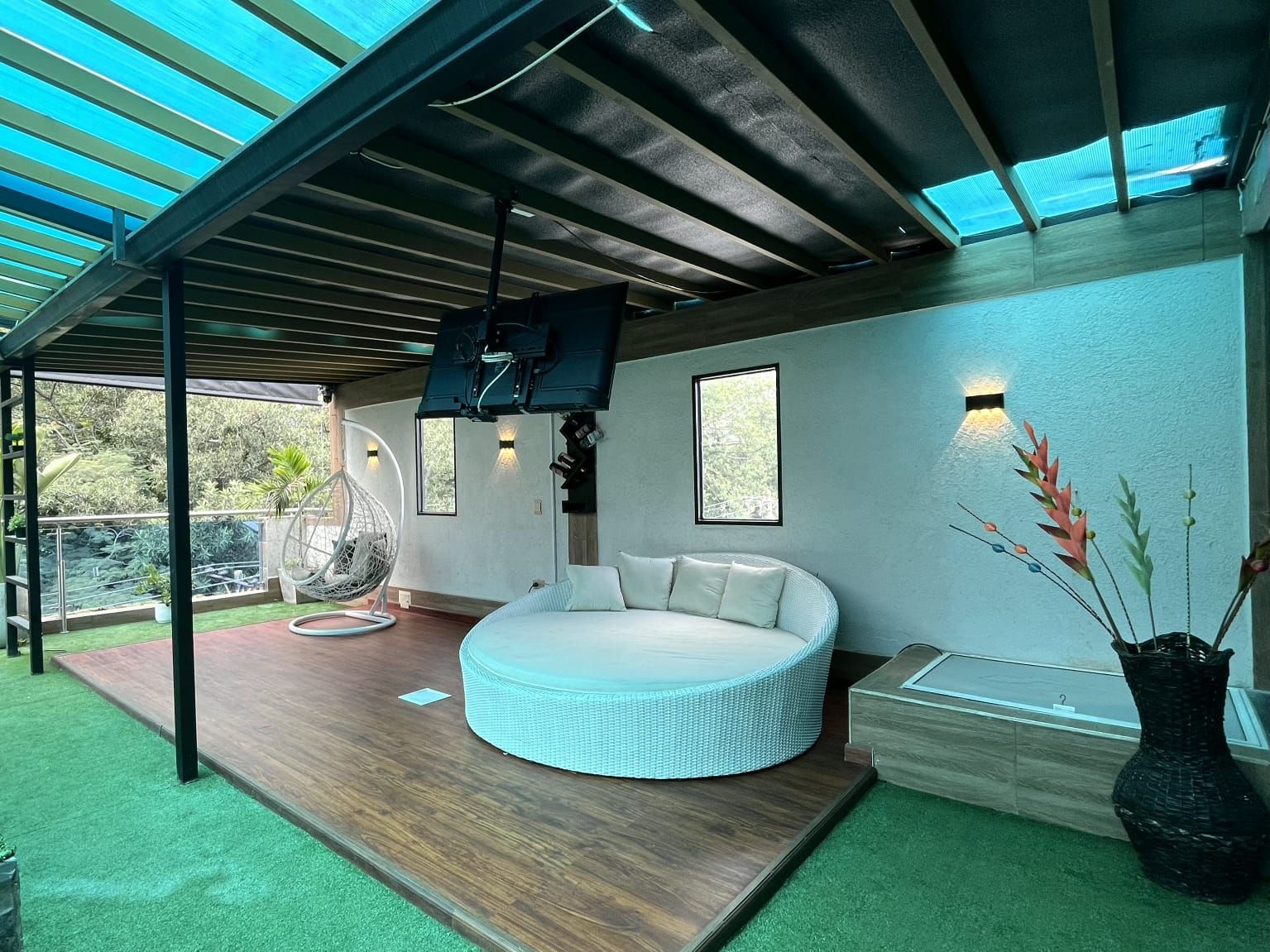 A modern bedroom with a circular bed, a hanging chair, and a large window.