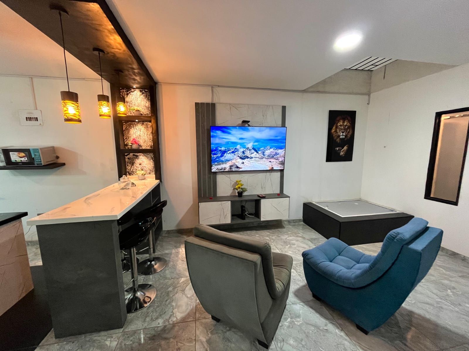 Una sala moderna con televisor de pantalla plana, zona de bar y asientos.
