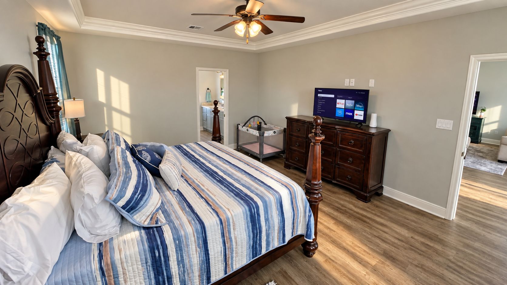 A bedroom with a bed, dresser, TV, and a ceiling fan.