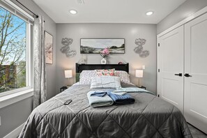 A bedroom with a bed, two bedside tables, a window, and a door.