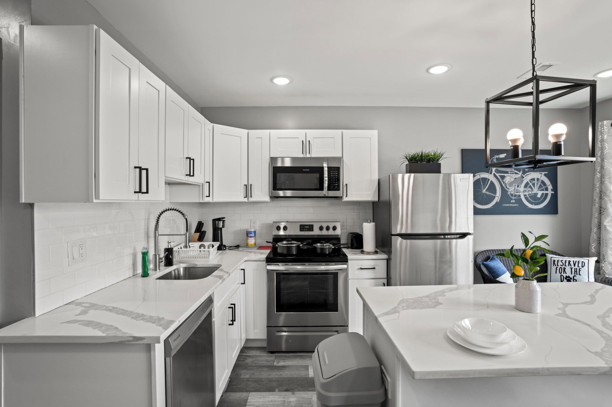 Una cocina moderna con armarios blancos, electrodomésticos de acero inoxidable y encimera de mármol.