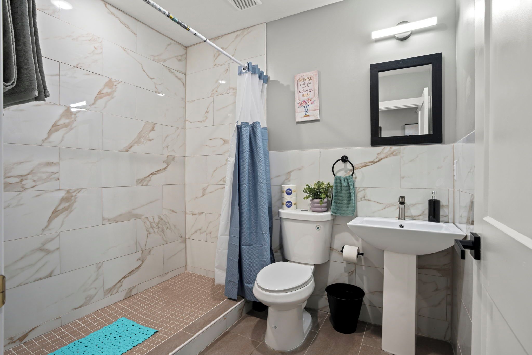 Un baño con ducha, inodoro, lavamanos y espejo.