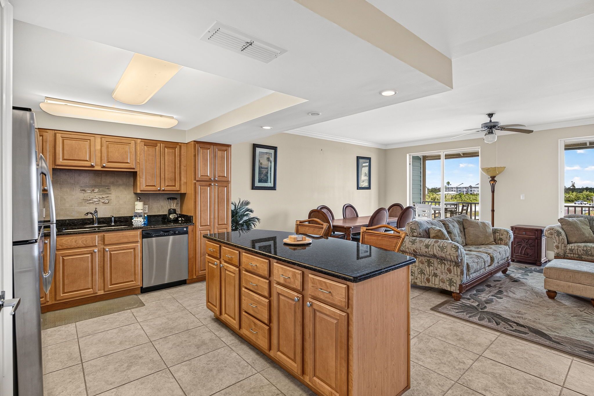 A spacious kitchen with wooden cabinets, a central island, and a dining area with a sofa and chairs.