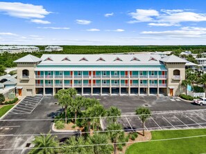 A multi-story hotel with a parking lot in front. - Stone’s Throw | 3Min to Beach | Pool, Hot Tub (Mexico Beach)