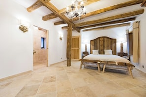 A bedroom with a wooden headboard, a bed with a white duvet, a wooden bench, and a chandelier. - Mountain lodge with pool in the Vosges (Ventron)