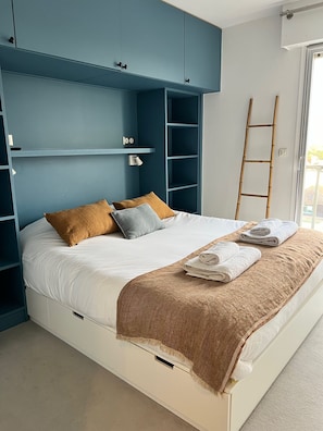 A bed with a white mattress, brown and grey pillows, a brown throw blanket, and neatly folded white towels. - Beautiful 4-bedroom apartment on the waterfront. (le touquet paris plage)