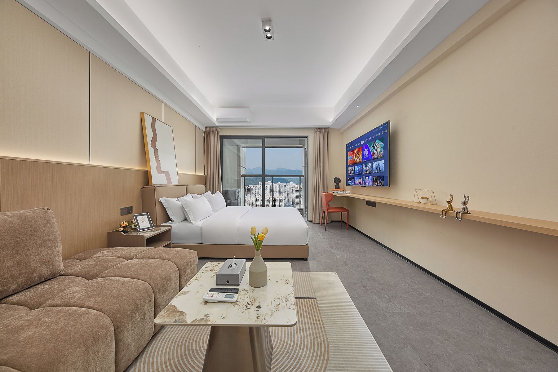 A hotel room with a bed, a sofa, a TV, and a desk with a laptop.