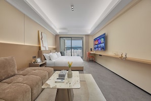 A hotel room with a bed, a sofa, a TV, and a desk with a laptop.