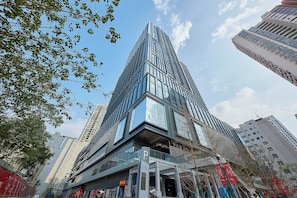 A modern high-rise building with a glass facade, surrounded by other tall buildings.