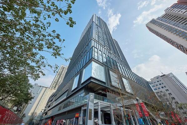 A modern high-rise building with a glass facade, surrounded by other tall buildings.