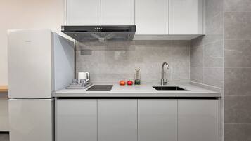 A modern kitchen with a built-in refrigerator, a stainless steel sink, and a range hood.