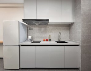 A modern kitchen with a built-in refrigerator, a stainless steel sink, and a range hood.