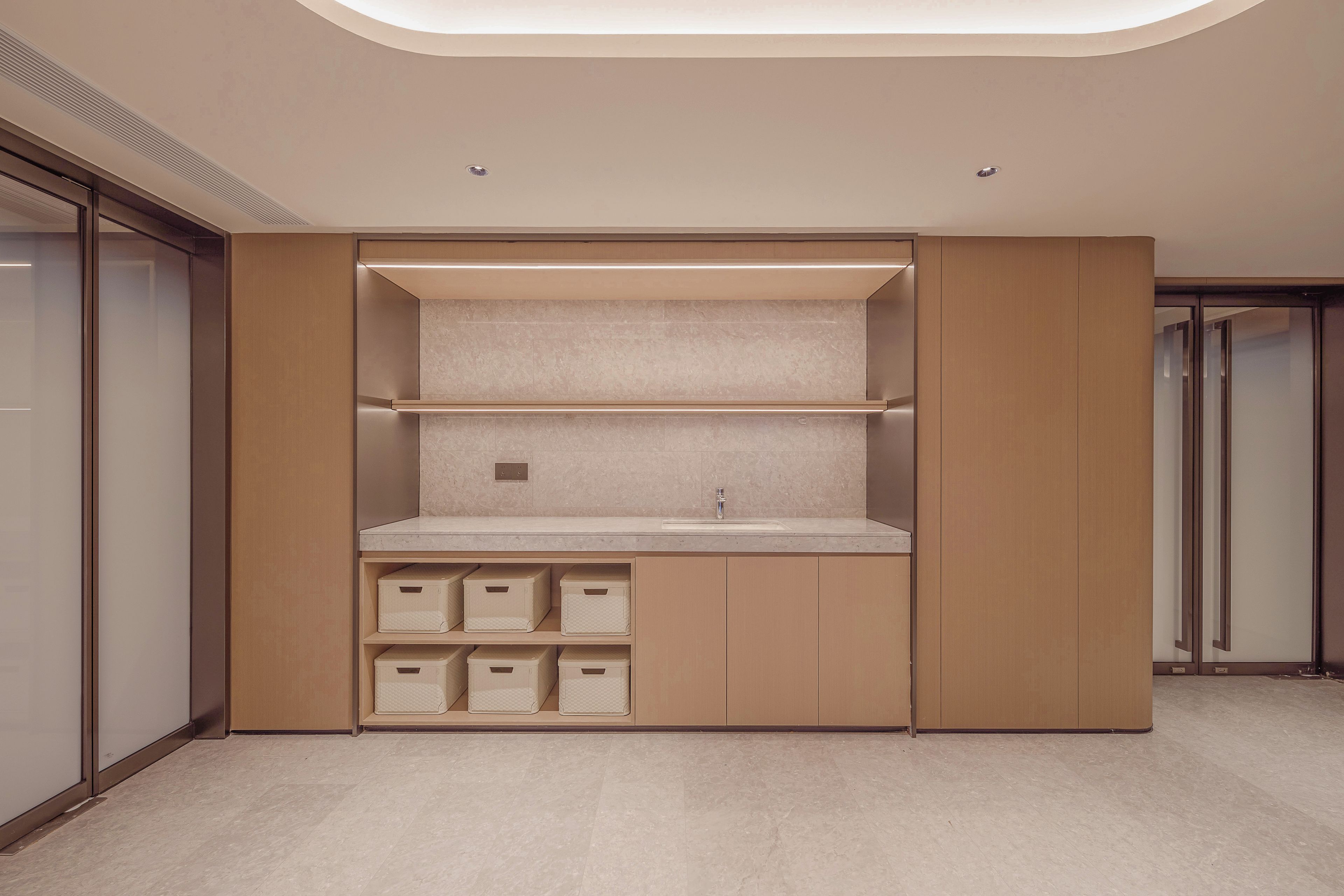 A modern bathroom with a built-in sink, storage cabinets, and a shower area.