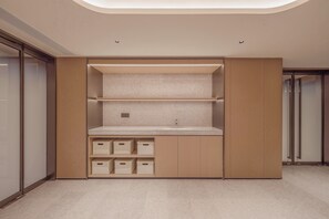 A modern bathroom with a built-in sink, storage cabinets, and a shower area.