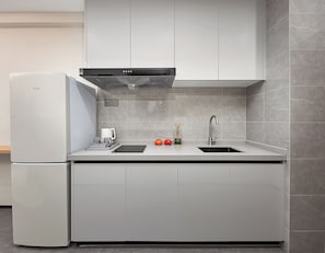 A modern kitchen with a built-in refrigerator, a stainless steel sink, and a range hood.