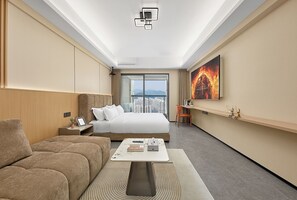 A modern hotel room with a large bed, a sofa, a coffee table, and a city view through the window.