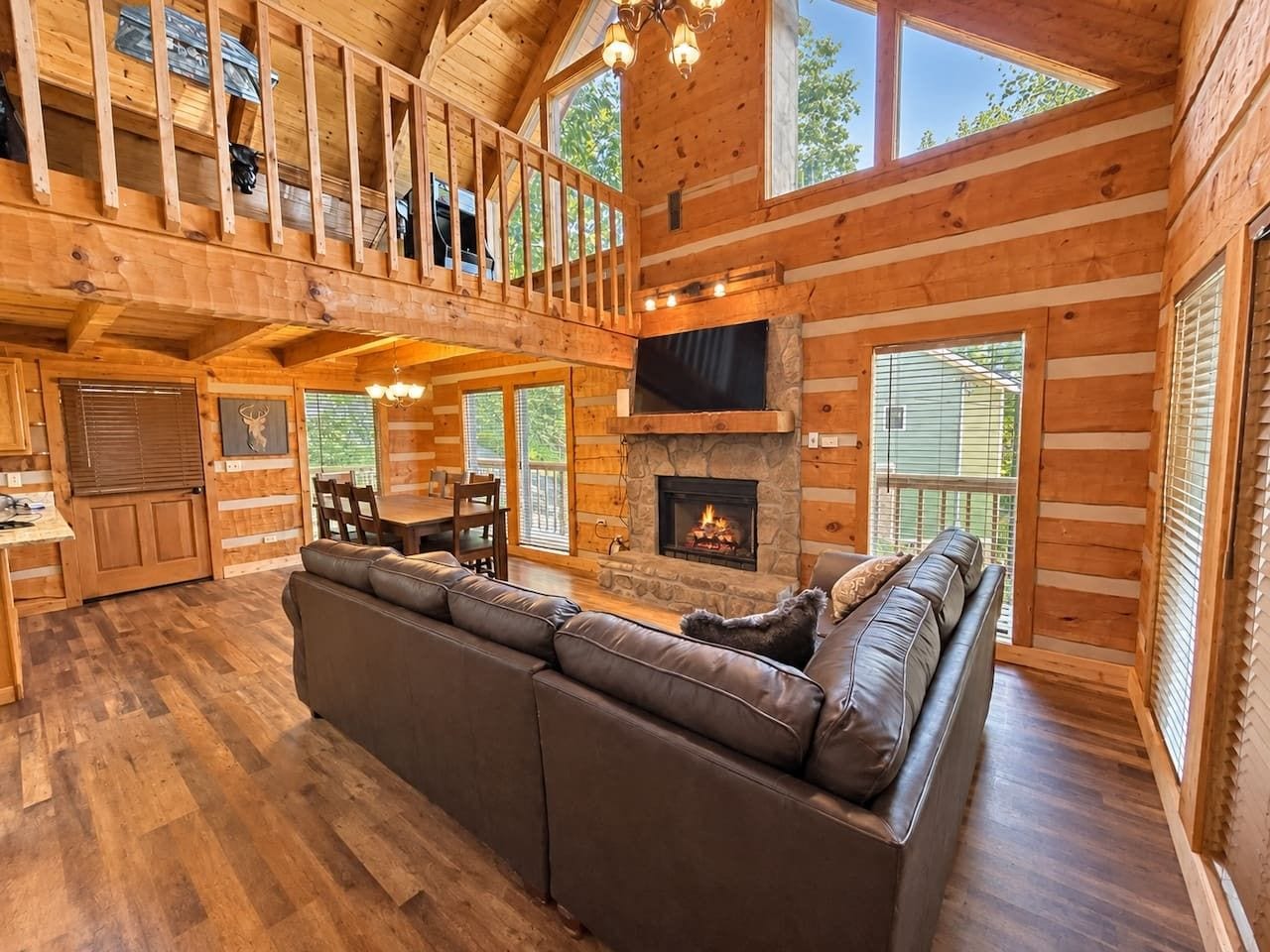 Un intérieur de chalet en bois spacieux, avec un grand canapé, une cheminée et un coin repas.