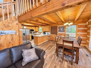A log cabin interior with a dining area, kitchen, and a living room with a leather couch. - Catnapping Cabin Hot Tub 7 minutes to main strip (Sevierville)