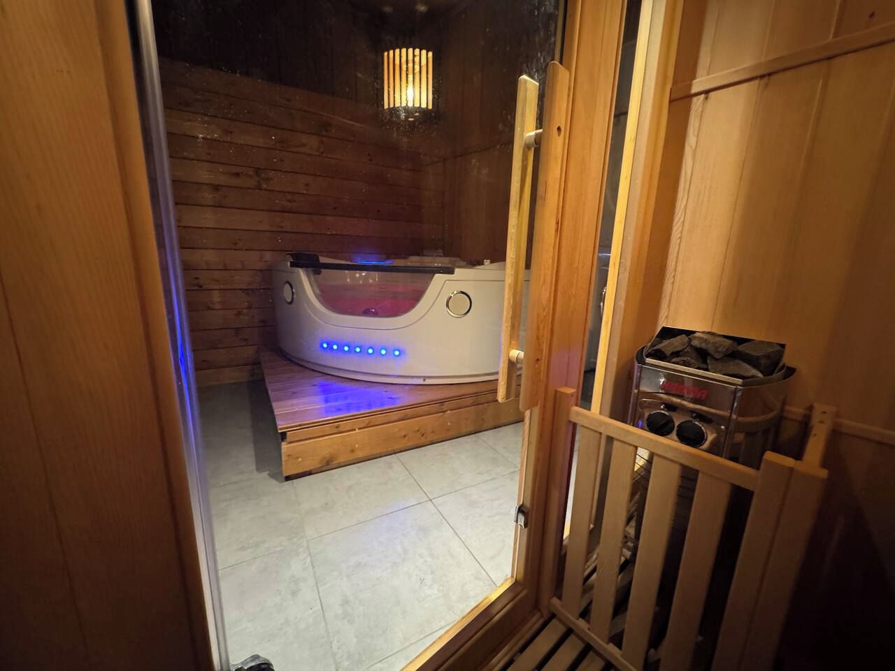 Eine Sauna mit einer Sitzbank und Bedienfeld, Holzwänden und einem gefliesten Boden.