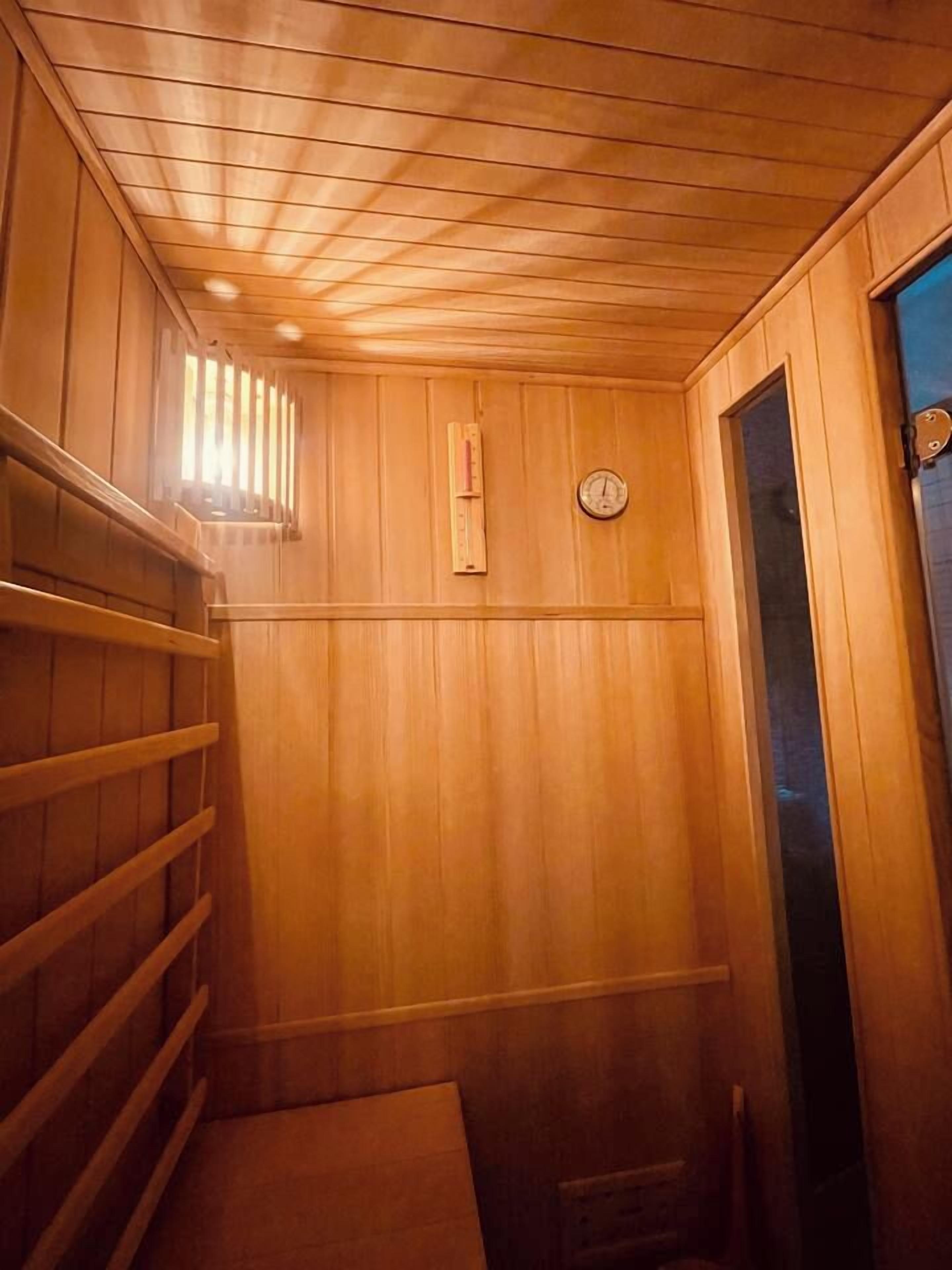 Un sauna avec des murs et un plafond en bois, une horloge et une porte.