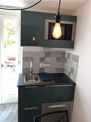 A compact kitchen with a built-in microwave, a sink, and a stovetop. - My Collioure - La Suite - Sauna, Spa & Beach (Collioure)
