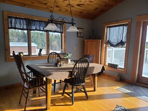 Un coin repas avec une table en bois, quatre chaises et un luminaire suspendu.