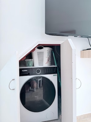 A compact laundry room with a front-loading washing machine, a dryer, and a small table.