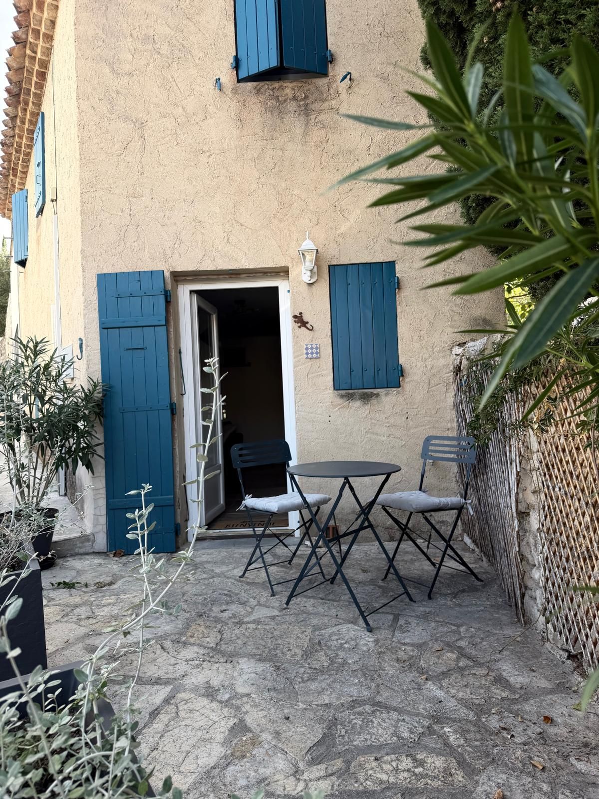 An outdoor patio with a table and chairs, a door, and a wall with a textured surface.