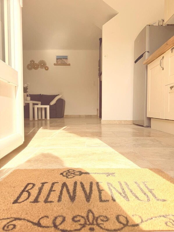 A hallway with a welcome mat leading to a dining area.